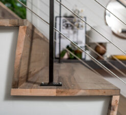 A close up view of the steel and stringer staircase in the Modern Sensitivity residence with dark grey and brown variegated wood floors and steps.