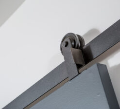 Detail shot of the sliding black barn door and steel track to the office in the Modern Sensitivity residence.