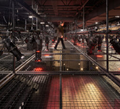 A man walking across the tension wire lighting grid suspended from the ceiling of the Luminary Arts Center.