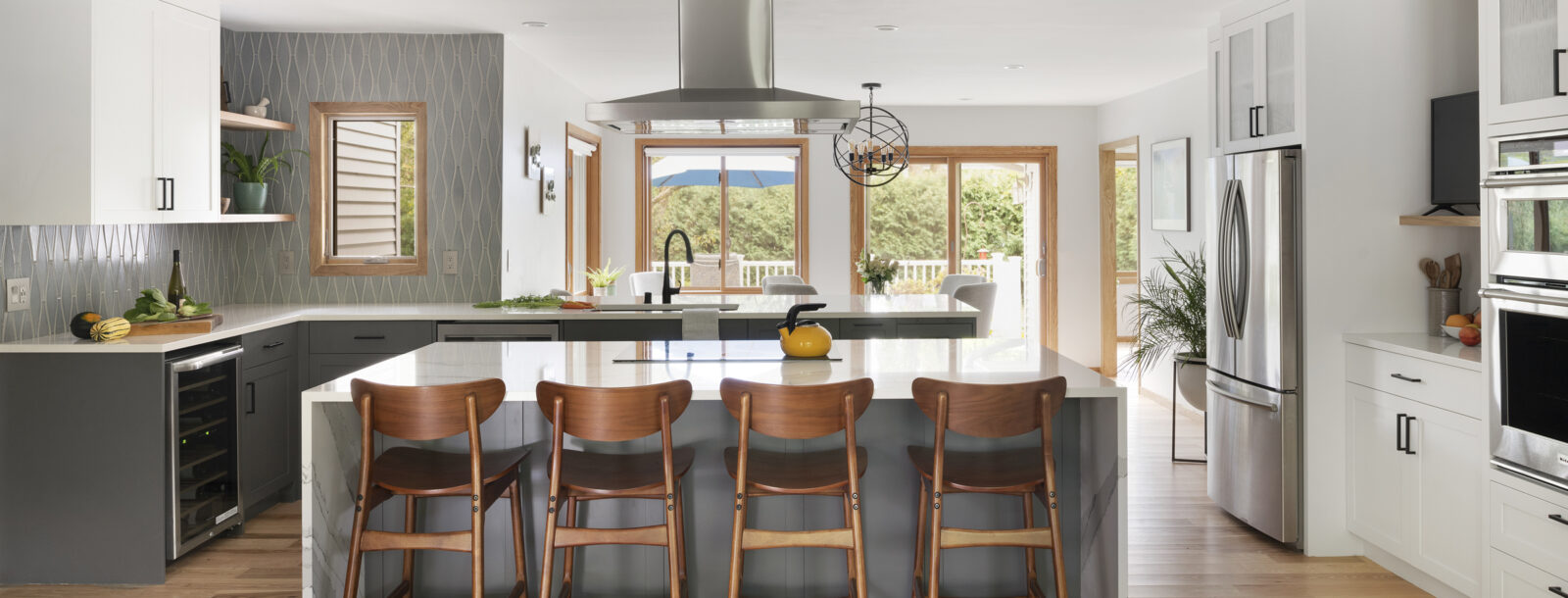 A view of the New Brighton Upgrade kitchen remodel showing the large, stone waterfall island with barstools.