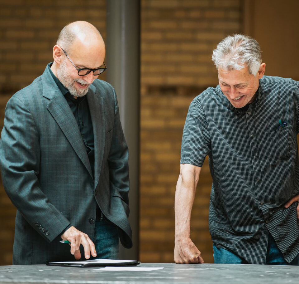 Two Shelter Architecture and Interior Design team members in discussion with one another smiling.