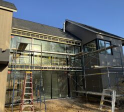The glass wall overlooking the outdoor courtyard the Sirkel Kjøre residence during construction. The floor to ceiling glass is installed, and the exterior siding on the home is being installed.