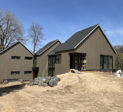 A front facing exterior image of the Sirkel Kjøre residence during construction with brown siding that mimics the bark of the surrounding trees.