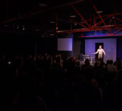 One male actor on stage at the HUGE Improv Theater performing a live show.