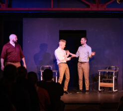 Three male actors on stage during a live performance at the HUGE Improv Theater.